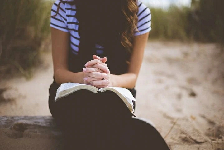 A lady praying with a Bible 