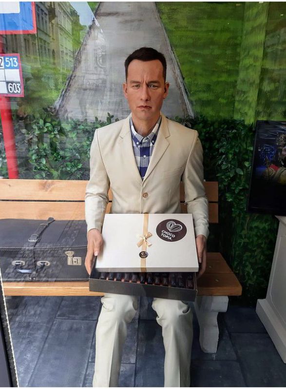 Forrest Gump sitting on a bench with a box of chocolates 